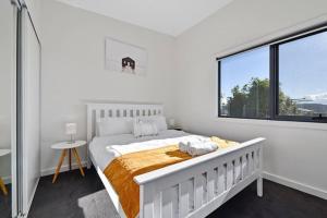 a white bedroom with a bed and a large window at Top Of The Bay-Modern Home With Spectacular Views in St Helens