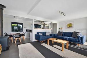 a living room with a blue couch and a table at Top Of The Bay-Modern Home With Spectacular Views in St Helens