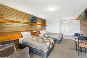 een hotelkamer met 2 bedden en een tafel en stoelen bij Allara Motor Lodge in Bendigo