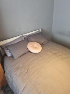 a bed with a white pillow on top of it at Lovely residential home 2 bed apartments in Goodmayes +3 photos