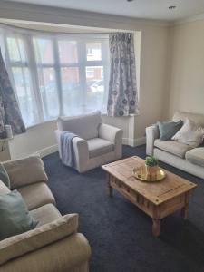 a living room with couches and a coffee table at Lovely residential home 2 bed apartments in Goodmayes