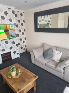 a living room with a couch and a coffee table at Lovely residential home 2 bed apartments in Goodmayes
