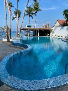 a swimming pool with blue water and palm trees at Wind Beach Resort in Ko Tao