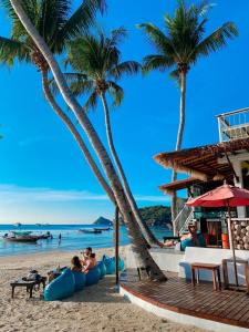 a beach with palm trees and people sitting on inflatables at Wind Beach Resort in Koh Tao