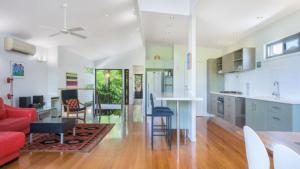 a kitchen and living room with a red couch and chairs at Moffat Retreat, Moffat Beach in Caloundra