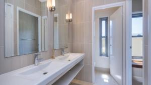 a white bathroom with a sink and a mirror at Moffat Retreat, Moffat Beach in Caloundra