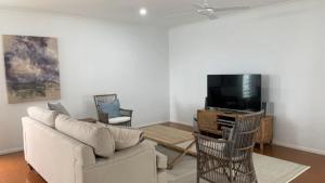 a living room with a couch and a tv at Saltys Place, Pet Friendly and Close To Beach in Caloundra