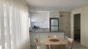 a kitchen with a table and chairs and a kitchen with white cabinets at Coastal Apt At Kings Beach, Stunning View in Caloundra