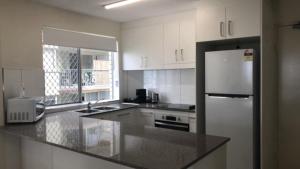 a kitchen with white cabinets and a stainless steel refrigerator at Coastal Apt At Kings Beach, Stunning View in Caloundra