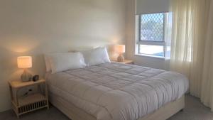 a bedroom with a large bed with two lamps on tables at Coastal Apt At Kings Beach, Stunning View in Caloundra
