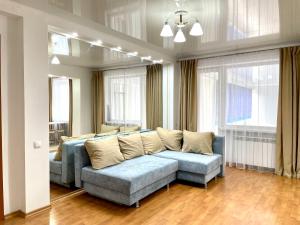 sala de estar con sofá azul y ventanas en Букетова 65 2-комн квартира с гостиничным сервисом с белым постельным, en Petropavlovsk
