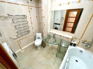 a bathroom with a tub and a toilet and a sink at Букетова 65 2-комн квартира с гостиничным сервисом с белым постельным in Petropavlovsk