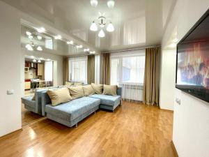 sala de estar con sofá y TV de pantalla plana en Букетова 65 2-комн квартира с гостиничным сервисом с белым постельным, en Petropavlovsk