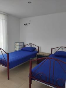twee bedden met blauwe lakens in een kamer bij Casa en Playa Privada - A pocos minutos de General Villamil Playas in Posorja