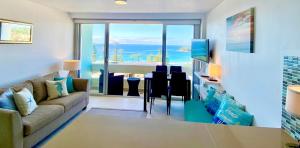 a living room with a couch and a view of the ocean at Manly Ocean Beach View Sunrise & Sunset in Sydney