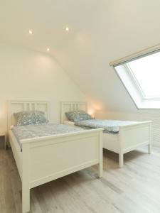 2 camas en una habitación blanca con ventana en Ferienhaus am Mühlenpfad, en Ottweiler