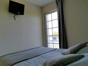 a bedroom with a bed with a television and a window at Les Roseaux - Piscine chauffee in Talmont-Saint-Hilaire +10 photos