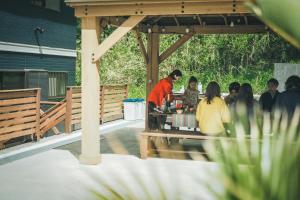 een groep mensen aan een tafel in een paviljoen bij Little Hermit by SANA in Tateyama