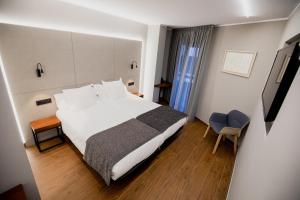 ein Hotelzimmer mit einem großen weißen Bett und einem Schreibtisch in der Unterkunft Les Closes in Andorra la Vella
