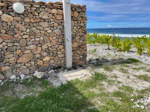 una pared de piedra con un poste junto al océano en Moorea Lodge en Temae