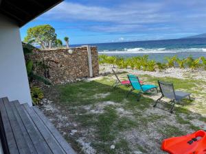 Temae的住宿－Moorea Lodge，一个带两把椅子和石墙的院子和大海