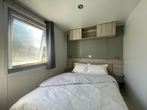 Un dormitorio pequeño con una cama y una ventana. en Mobil home XXL - Bord LAC - CAMPING Les Viviers - Lège cap ferret, en Lège-Cap-Ferret 56 fotos más