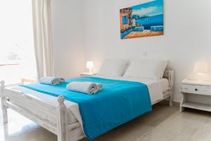 a white bedroom with a white bed with blue sheets at Villa Kallithea in Parga