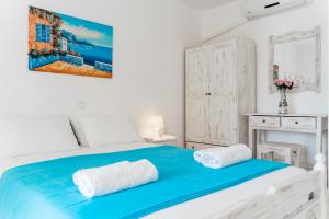 um quarto branco com uma cama azul e 2 toalhas em Villa Kallithea em Parga