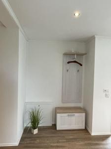 a room with a white wall with a cabinet and a plant at Ferienwohnung Wiehelund - Kleinwiehe in Lindewitt