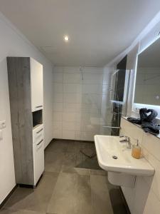 a white bathroom with a sink and a refrigerator at Ferienwohnung Wiehelund - Kleinwiehe in Lindewitt