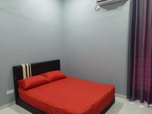 - un petit lit avec un oreiller rouge dans l'établissement Alias Residence - Homestay Kubang Kerian, à Kota Bharu