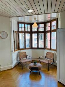 Zimmer mit 2 Stühlen, einem Tisch und Fenstern in der Unterkunft Apartment Marktplatz 2 in Basel