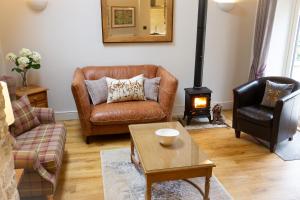 a living room with a leather couch and a wood stove at Luxury Barn near Stamford in Wansford
