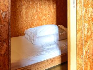 a bed in a wooden room with a pillow at Kawaramachi Domitory in Takamatsu