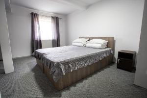a bedroom with a bed with white sheets and a window at Pensiunea Poarta Apusenilor in Moldoveneşti