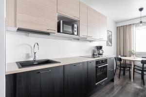 a kitchen with black cabinets and a sink and a table at Newly Renovated 1BR Home that Hosts up to 8 Guests - Hosted by 2ndhomes in Tampere +5 photos