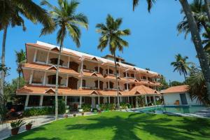 a large building with palm trees in front of it at The Sanctum Spring Beach Resort in Varkala