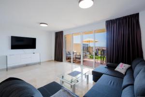 a living room with a blue couch and a television at Residencial Playa de La Arena in Puerto de Santiago
