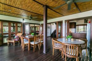 ELYSIA NONGSA 91 BATAM LUXURY VILLA في نونغْسا: غرفة طعام مع طاولات وكراسي خشبية