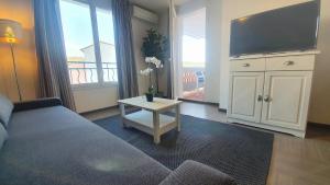 - un salon avec un canapé, une télévision et une table dans l'établissement Le Lavandin - T3 Piscine & Climatisation, à Gréoux-les-Bains