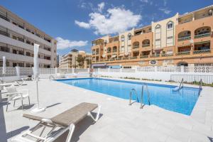 a swimming pool with chairs and a building at Apartment Arce Frontline seaview in Nerja