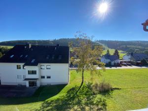 a white house in a field with the sun in the sky at Fewo Bergperle in Willingen