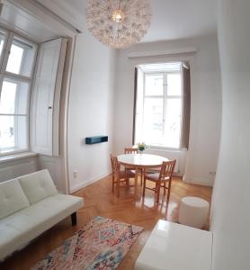 Sobieski Stefansdom Apartments في فيينا: غرفة معيشة مع طاولة وكراسي وثريا