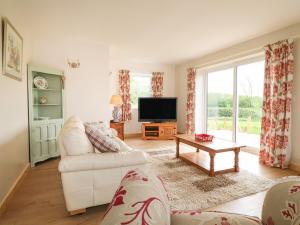 a living room with a white couch and a tv at Orchard Cottage in Derby