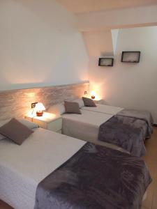 a hotel room with three beds and two lamps at A Parada do Camiño in Arzúa