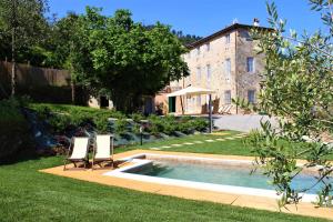 - une piscine dans une cour avec 2 chaises et un bâtiment dans l'établissement Casa Locci, à Capannori