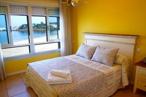 een slaapkamer met een bed met gele muren en ramen bij Desconectaengalicia Paseo Silgar, 4 dormitorios in Sanxenxo