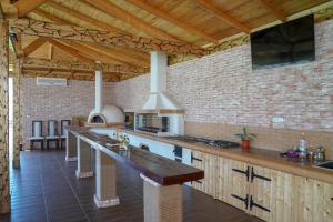 a large kitchen with a bar with a tv on a brick wall at Pensiunea Danubio in Dunavăţu de Jos