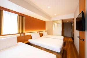 a hotel room with two beds and a flat screen tv at karaksa hotel grande Shin-Osaka Tower in Osaka