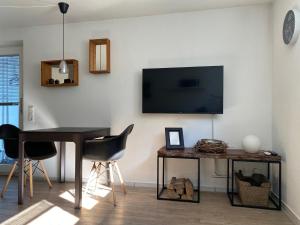a living room with a table and a television on a wall at Ferienwohnung bei Freiburg in Holzhausen